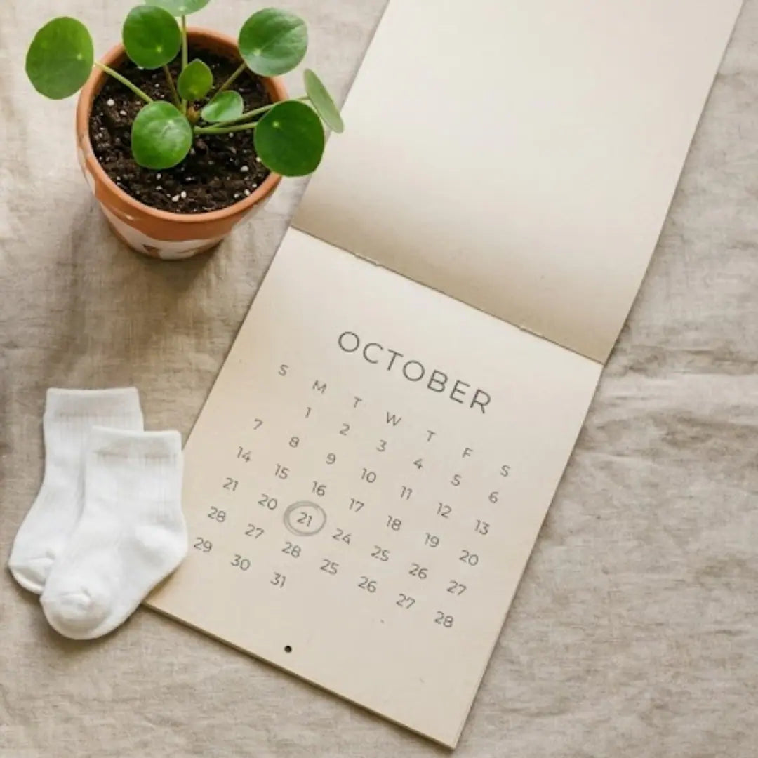 Composition évoquant la préparation à l'arrivée d'un enfant (calendrier avec une date entourée, vêtements pliés), sans montrer de sac précis, pour illustrer la question du "bon moment" sans trancher visuellement en faveur d'un choix avant/après.