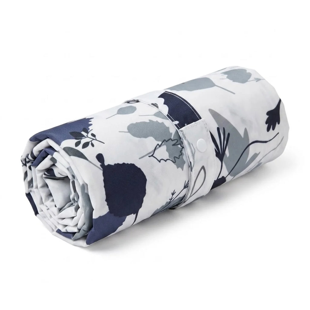 Tapis à langer roulé et fermé par sa sangle à motifs et bouton-pression, réduit à un format compact qui se glisse dans n'importe quel sac à langer, sac à main ou vide-poche de poussette sans prendre de place.


