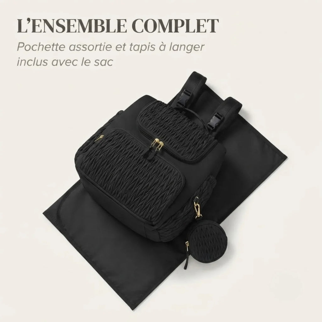Mise en scène du sac à langer à poches isothermes avec le tapis à langer déplié en dessous et la pochette ronde assortie posée à côté, fond crème.