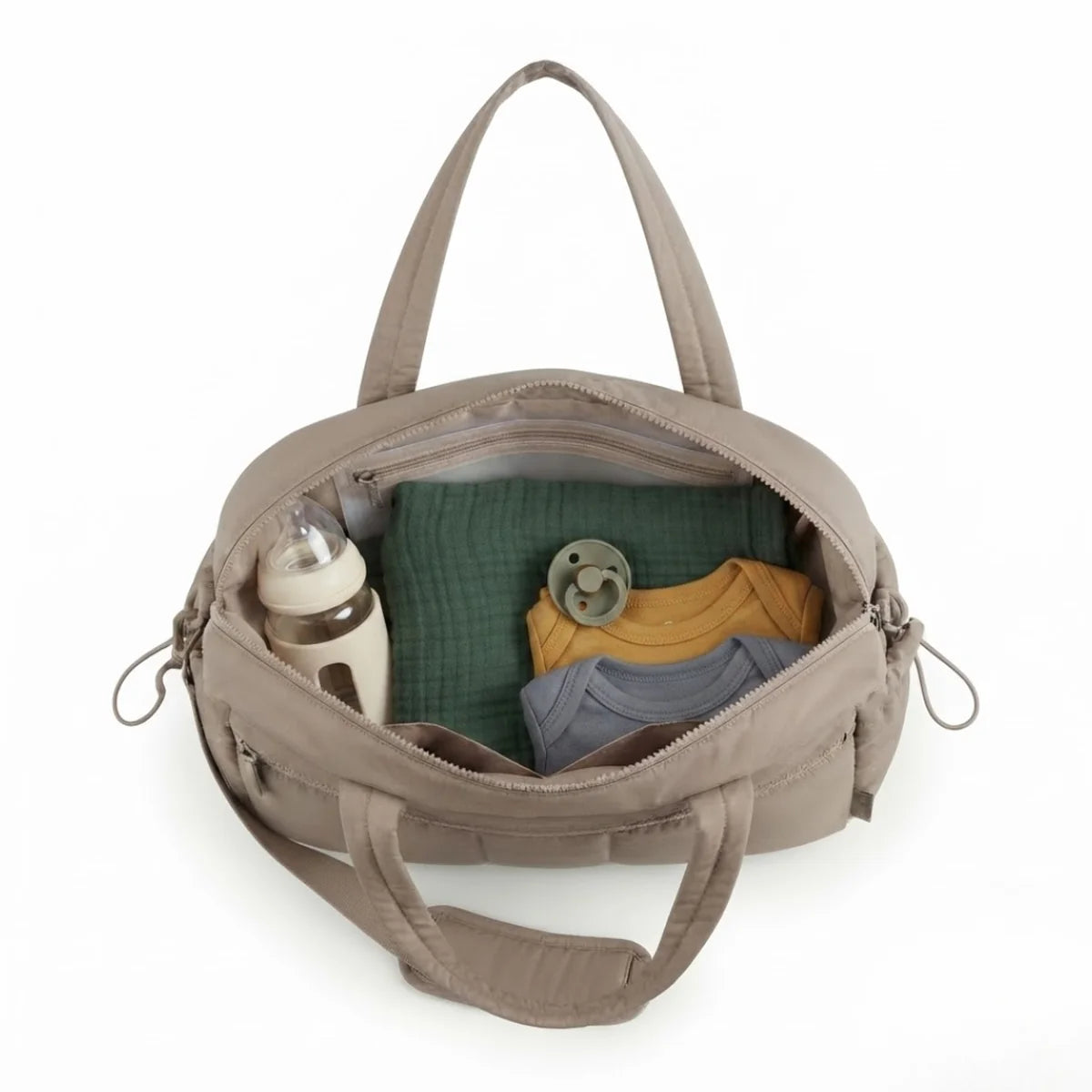 Vue du sac à langer déperlant matelassé ouvert, vue de dessus, avec biberon, lange vert, tétine et deux bodies (moutarde et gris) rangés à l'intérieur.
