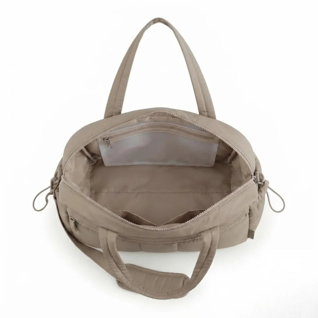 Vue du sac à langer déperlant matelassé coloris taupe, intérieur vide avec poche zippée translucide visible.