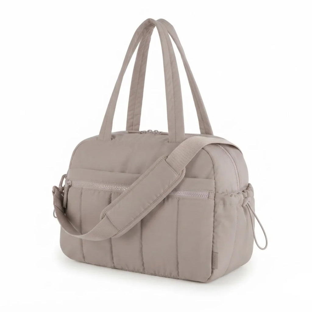 Vue du sac à langer déperlant matelassé coloris taupe, vue de trois quarts avec bandoulière visible.