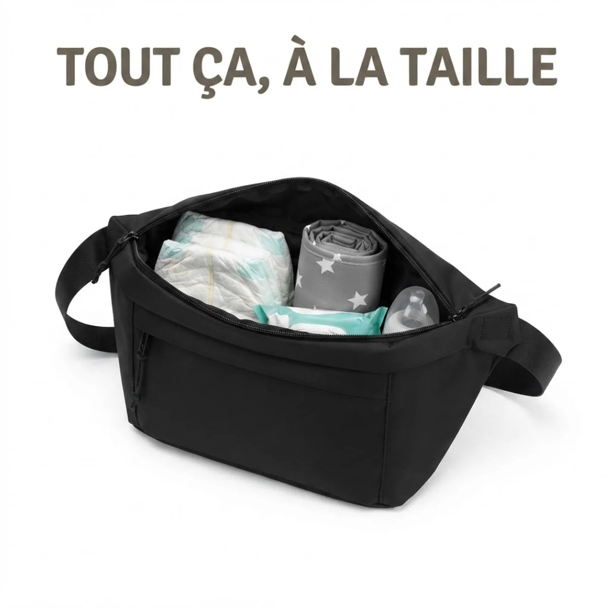 Vue du sac banane à langer grand format ouvert. L'intérieur montre deux couches pliées, un tapis à langer gris à motif étoiles enroulé, un paquet de lingettes et un biberon, rangés côte à côte dans le compartiment principal.