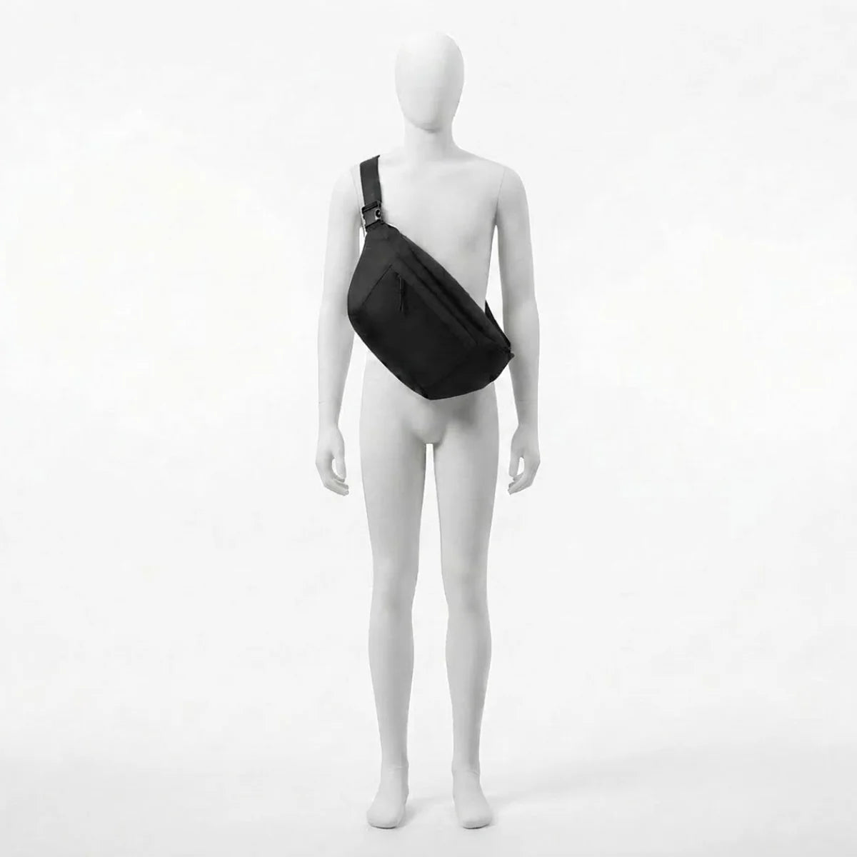 Vue du sac banane à langer grand format porté par le mannequin, sangle passant de l'épaule à la hanche opposée, boucle de réglage visible au niveau de l'épaule.