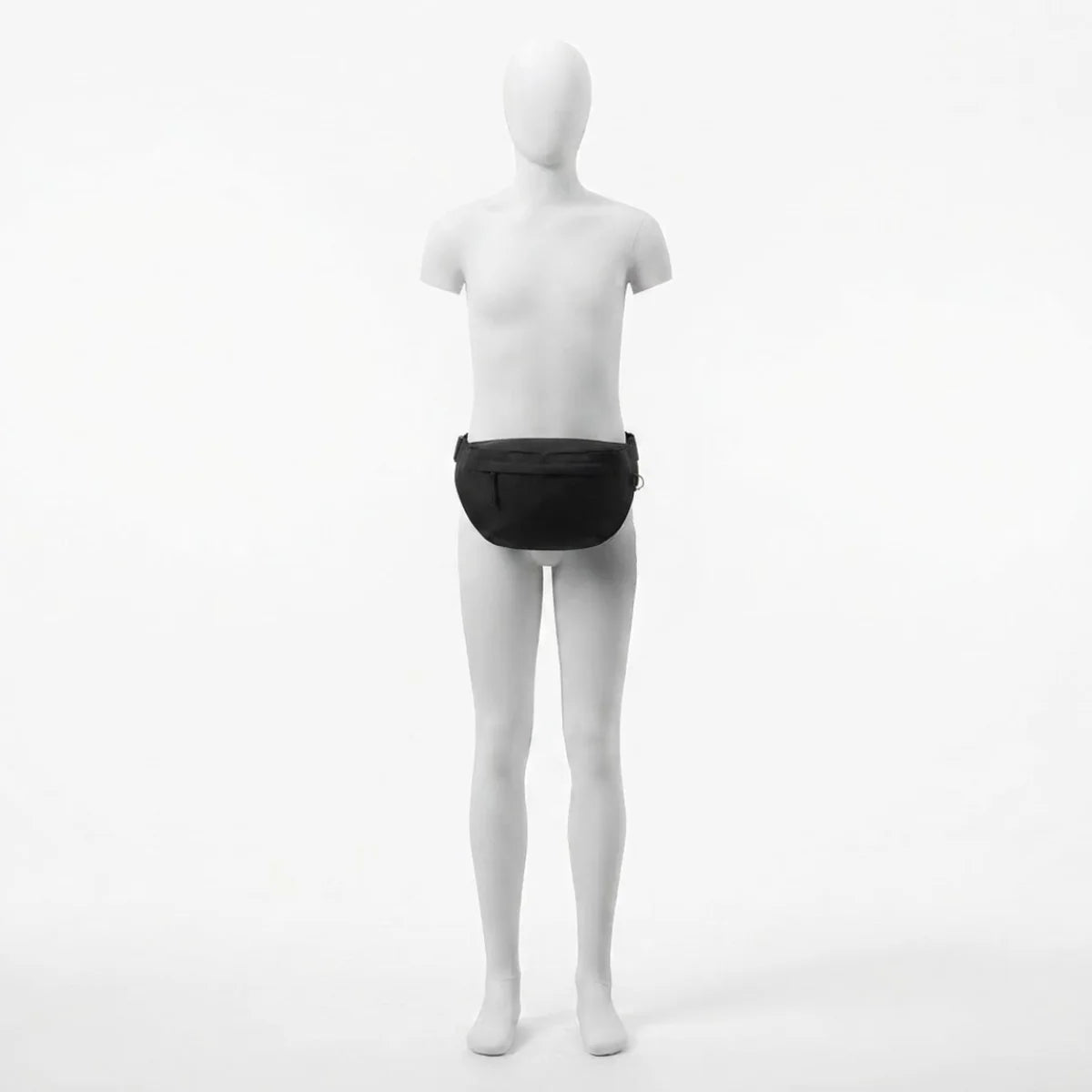 Vue du sac banane à langer grand format porté à la taille par le mannequin, positionné bas sur le bassin, silhouette pleine et arrondie du sac bien visible de face.